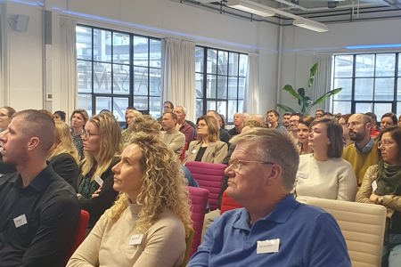 Mensen luisteren naar een presentatie tijdens de PGAx Klantendag