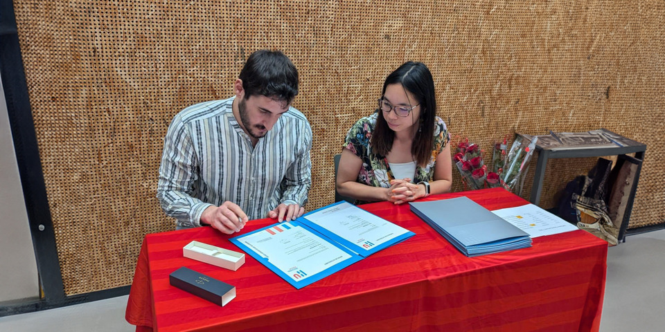 omar afstuderen, diploma ondertekenen aan tafel met docent