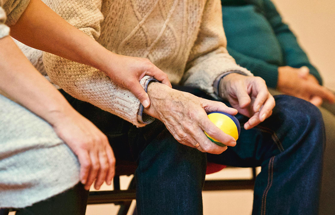 Ontwikkeld Samen Met De Zorg: Begeleider legt hand op de knie van de cliënt