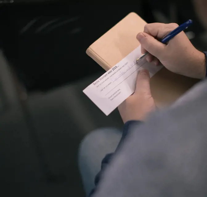 Klant noteert wat op een briefje tijdens de Pgax Klantendag van 7-12-2023